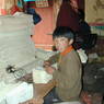 A young boy threading pages at the Derge Publishing House.