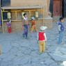Tibetan children playing near prayer wheels outside the Assembly Hall.