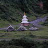 A stupa with three other stupas made of piles of rocks.