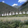 One end of a long row of stupas set alongside a road.