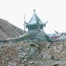 A pile of rocks and a pagoda wrapped in prayer flags at the crest of the ? Pass.