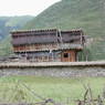 A Tibetan log house with woven brush shading device on the second story.