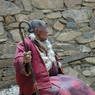 An elderly nun resting next to a building.
