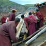 A group of monks loading logs onto a truck.