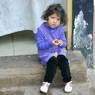A young Tibetan-American girl eating a snack on the patio doorstep.