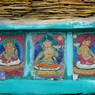 Close-up of painted carvings of buddhas framed in a pile of prayer stones. ??