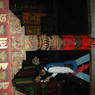 Tibetan pilgrims passing by a carved and painted column.