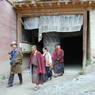 Tibetan laypeople and a nun circumambulating a monastery building.
