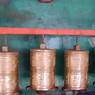 A row of prayer wheels in front of a mural of Green Tara along a circumambulation route around the monastery.