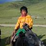 A young nomad boy riding a yak.