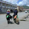 A Tibetan couple riding yaks decorated for the festival on the street in Serta.