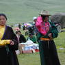 Young Tibetan women wearing black chubas at the festival site.