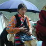 A Tibetan woman wearing a floral shirt opening her purse.