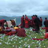 Monks picking up paper prayer flags on top of one of the hills above Larung Gar.