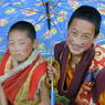 Two young monks under an umbrella on top of the hill.