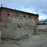 Mantra om mani padme hum in white letters on back wall of monastic temple and three stupas in front